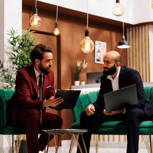 Corporate team reviewing project ideas at international meeting in hotel lounge area, discussing with colleague at business conference. Entrepreneurs travelling for work at resort.