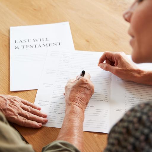 Female Friend Helping Senior Woman To Complete Last Will And Testament At Home