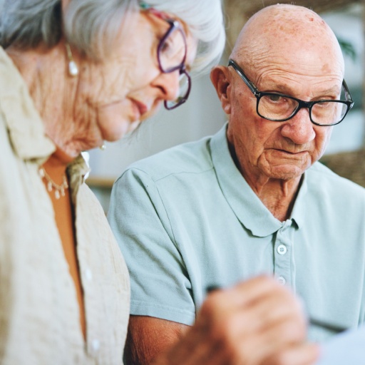 Senior couple, paperwork and reading in home for finance, life insurance and planning for assets. P.