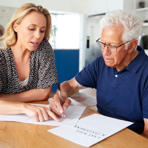 Woman Helping Senior Man To Complete Last Will And Testament At Home